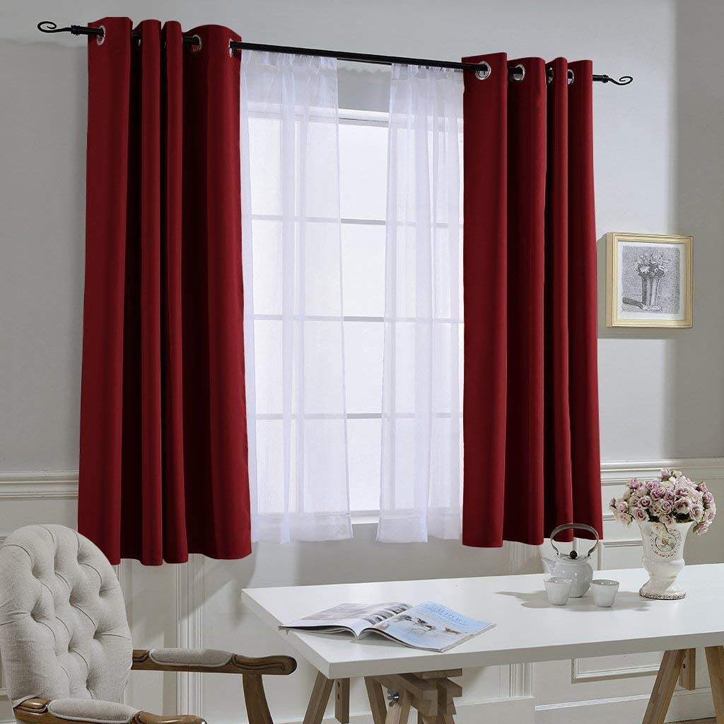Two deep red grommet blackout curtains with white sheers on a window rod, perfect for noise reducing living room & bedroom privacy.