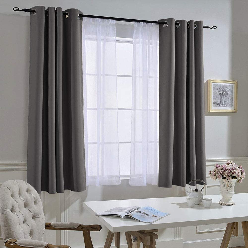 Two dark gray grommet blackout curtain panels with white sheer curtains in a living room or bedroom, ideal for noise reduction.