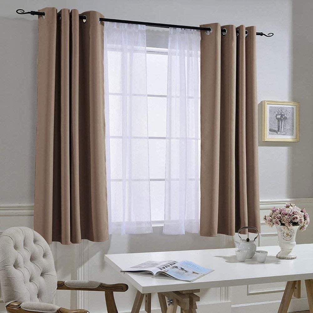 Pair of brown grommet noise reducing blackout curtains with sheer panels on a window in a living room setting.