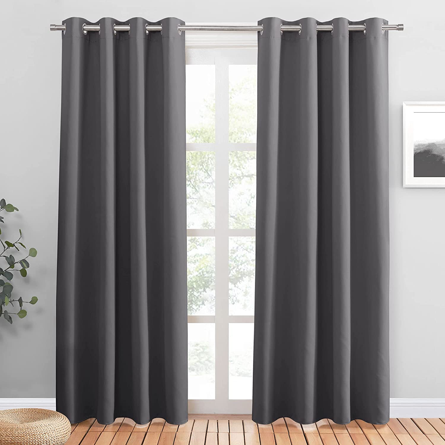 Two charcoal gray grommet blackout curtains drawn across a window, providing noise reducing and light blocking privacy for a living room or bedroom.
