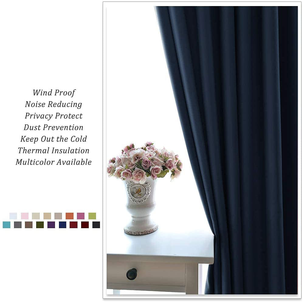 Dark blue noise reducing blackout grommet curtain in a modern living room or bedroom, with a vase of pink flowers.