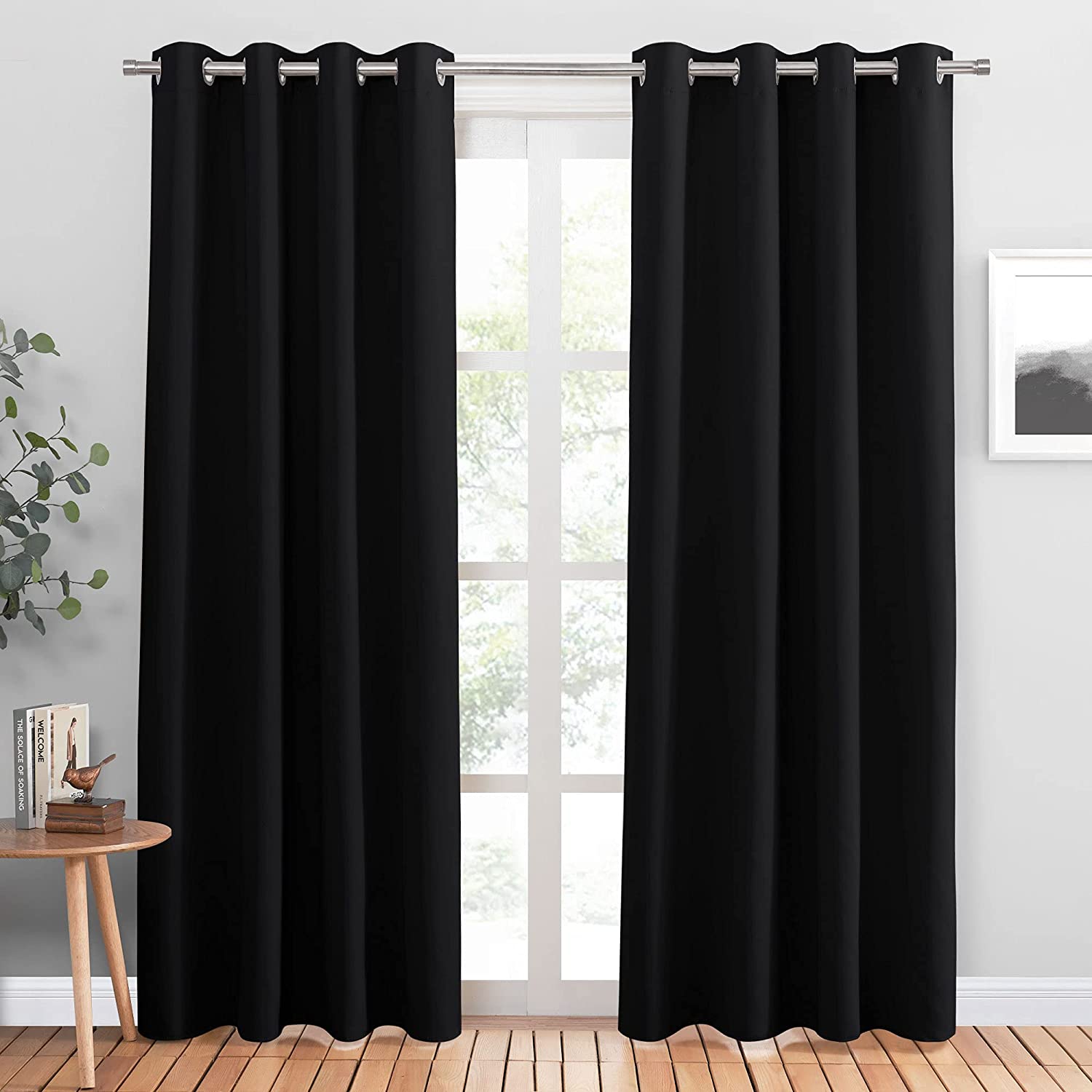 Two black grommet noise reducing blackout curtain panels for living room or bedroom privacy.