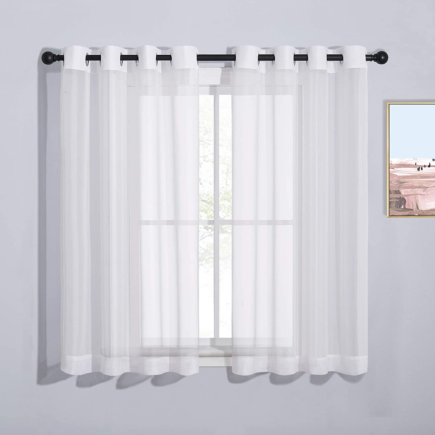 Two white solid sheer voile curtains with grommet top on a window for bedroom and living room privacy.