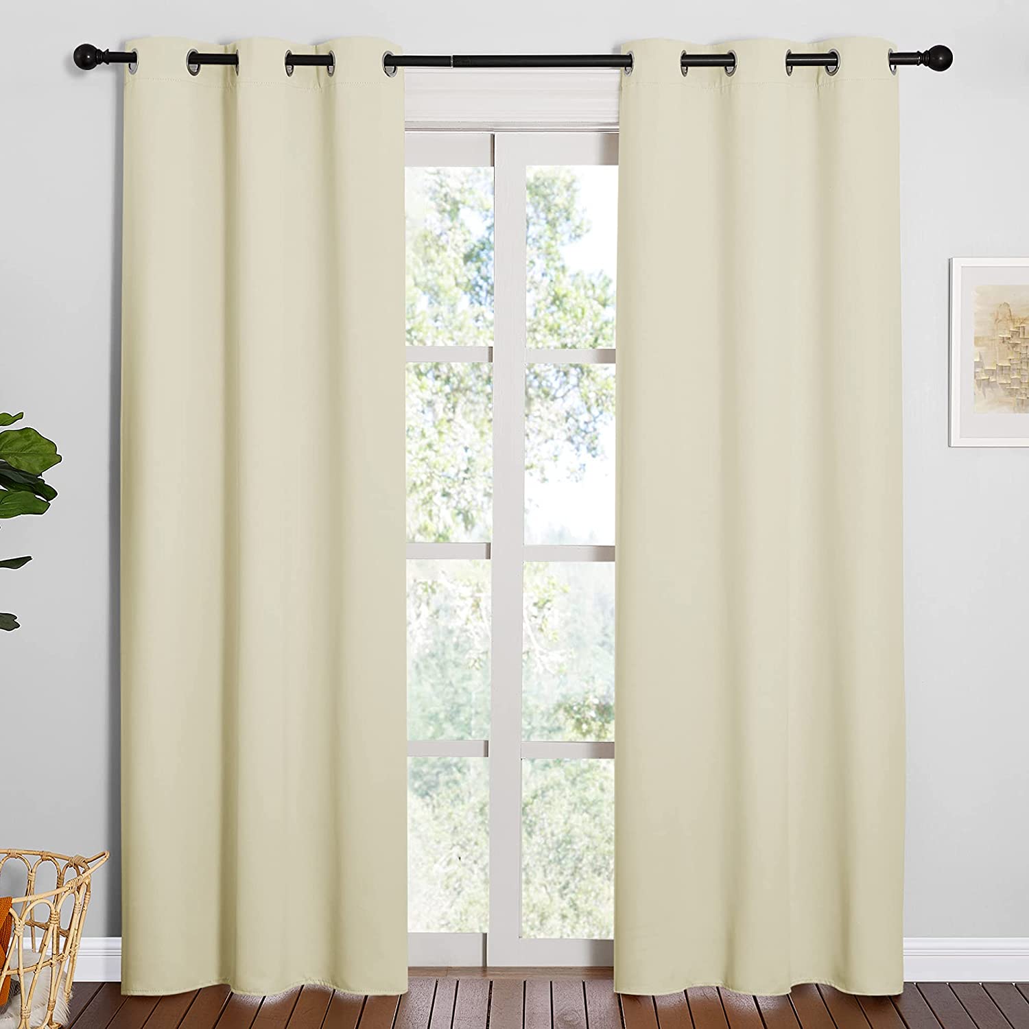 Two cream grommet top thermal insulated blackout curtain panels hung over a living room window.