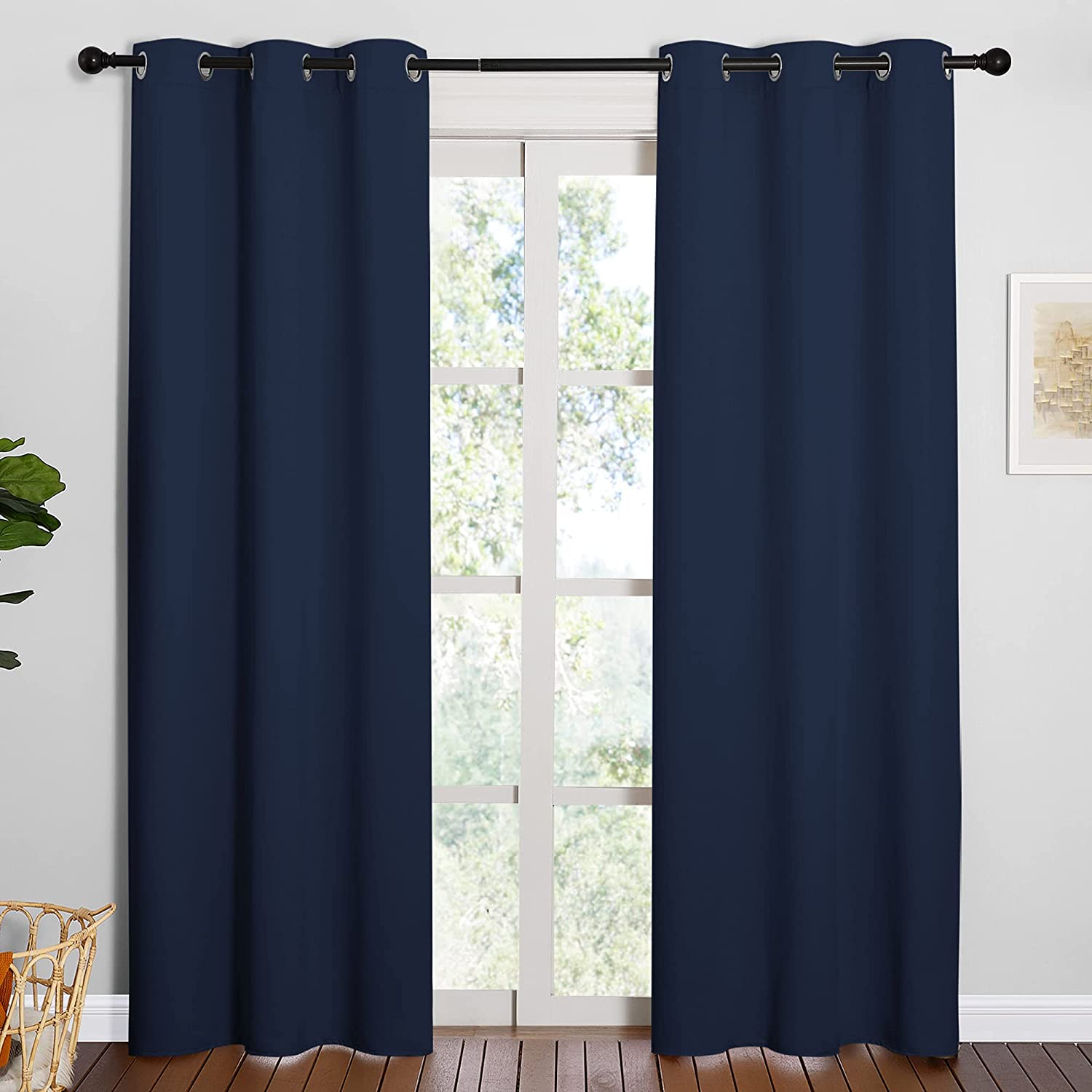 Navy blue grommet thermal insulated blackout curtains (2 panels) for a living room, hanging from a rod, partially obscuring a window.