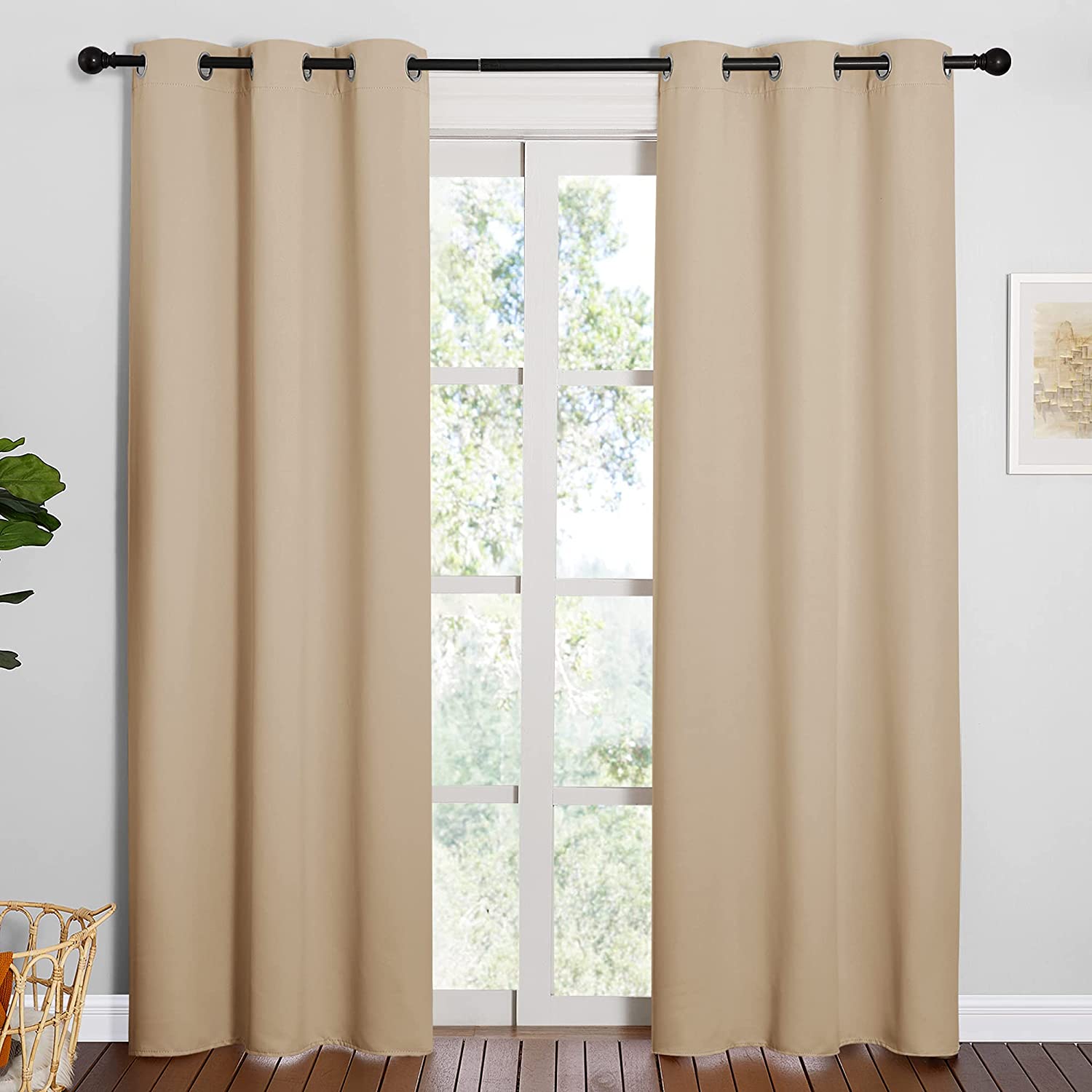 Two beige thermal insulated blackout grommet curtain panels for living room, hanging on a rod over a bright window.