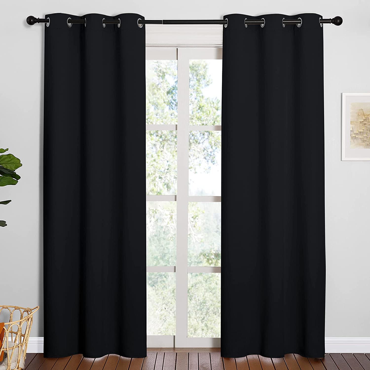 Two black thermal insulated blackout grommet curtains covering a living room window.