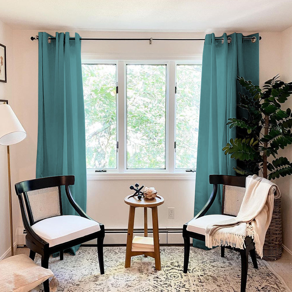 Two teal grommet thermal insulated blackout weave curtain panels in a living room, framing a window with furniture.