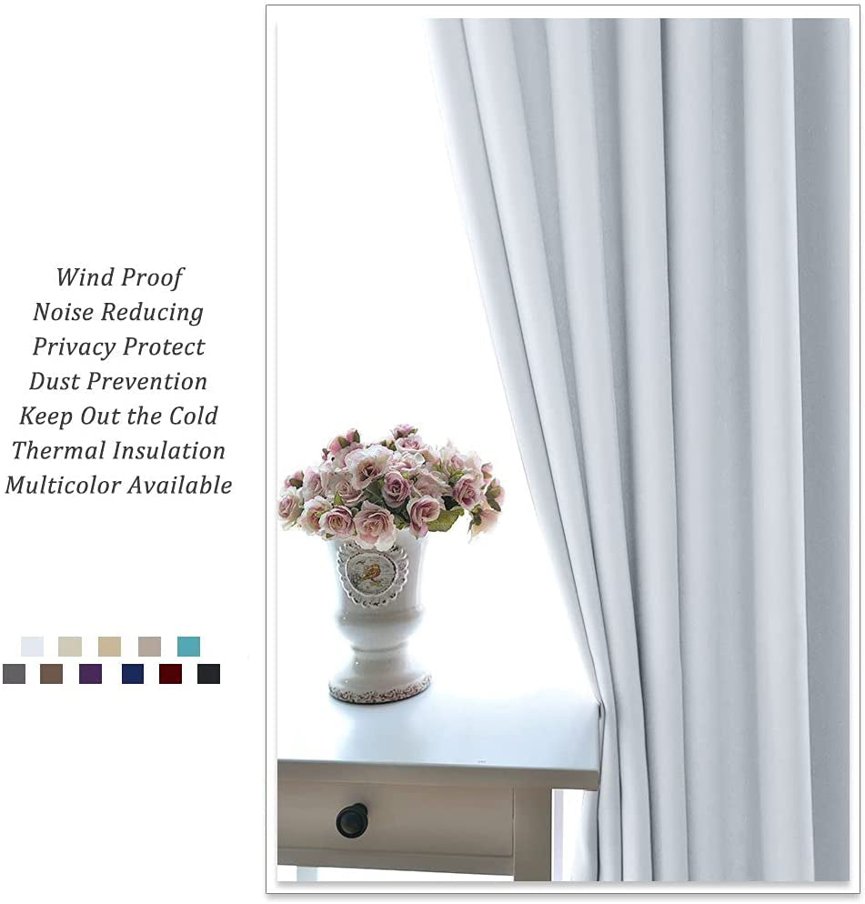 Light-colored thermal insulated blackout curtain panel elegantly drapes by a window. A vase of pink flowers adorns a white side table.