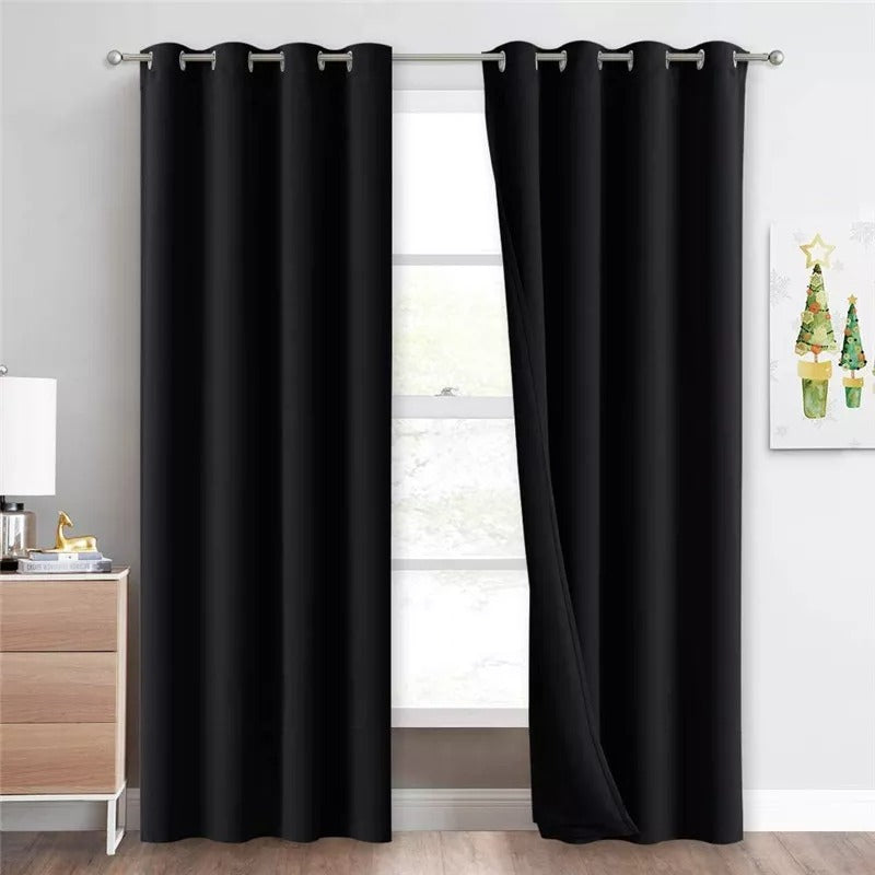 Two black grommet blackout curtains, 3-layer thermal & soundproof, hanging in a living room over a window.