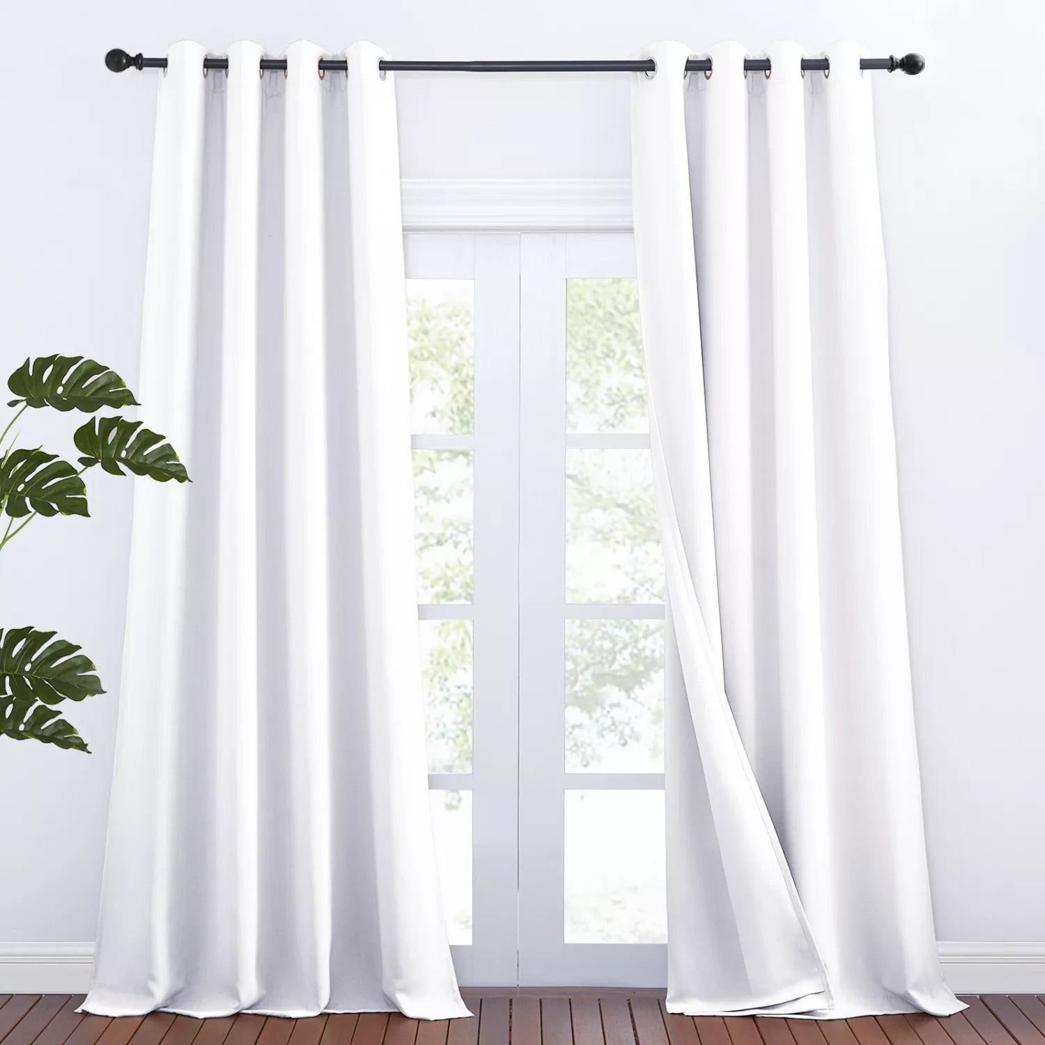 White grommet 3-layer thermal soundproof blackout curtains, 2 panels, partially open over a glass door and wood floor.