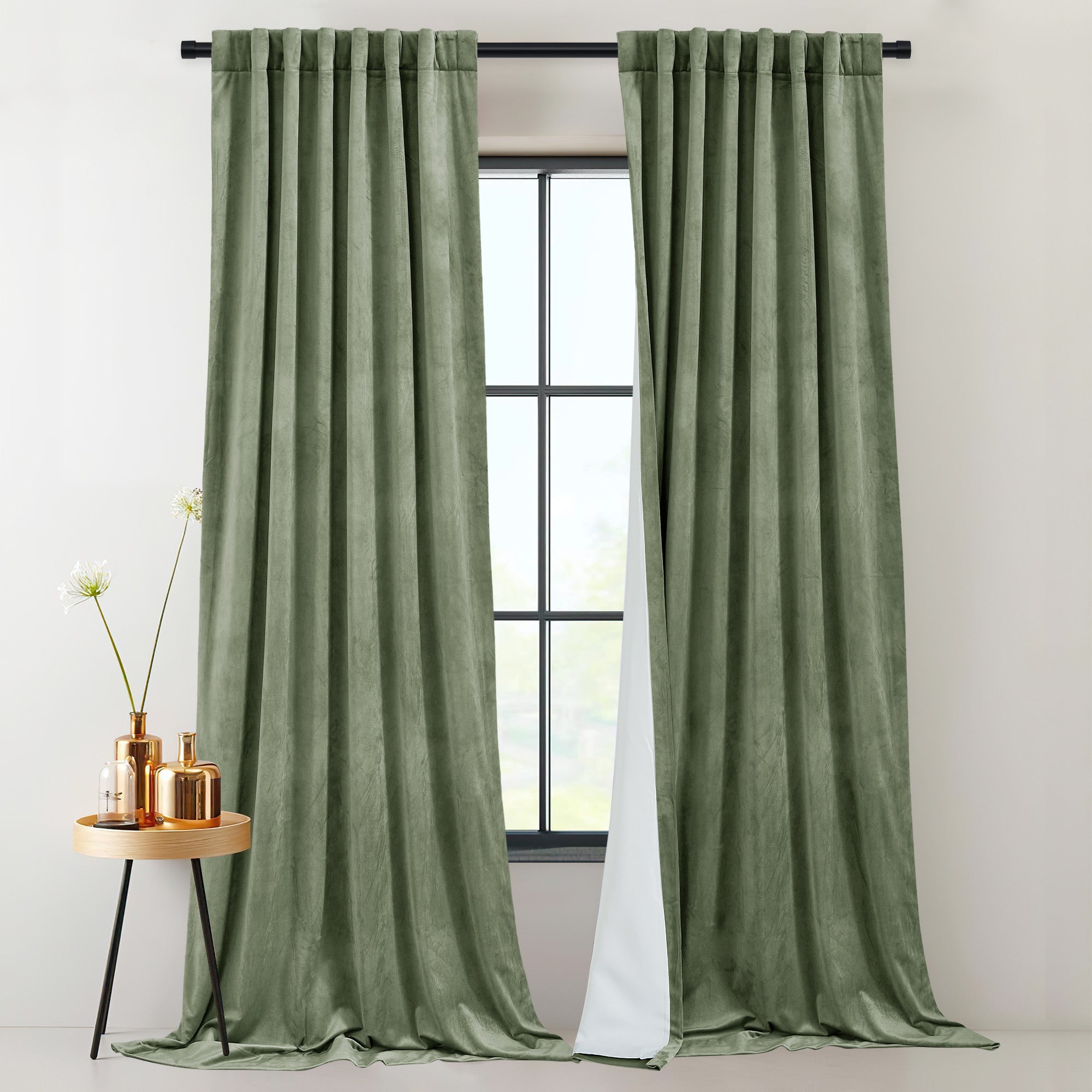 Two green velvet thermal insulated light blocking curtains with rod pocket & back tab, partially open by a window, revealing white lining.