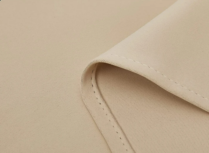 Close-up of KGORGE weatherproof light beige blackout outdoor curtain fabric sample with subtle texture & durable stitching.