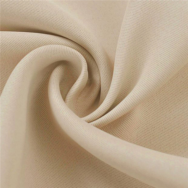 Close-up of folded, textured beige blackout curtain fabric sample, highlighting its heavyweight polyester material.