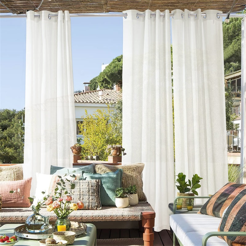 Sunny patio with two white faux linen sheer grommet outdoor curtains, enhancing privacy and creating a serene outdoor oasis.