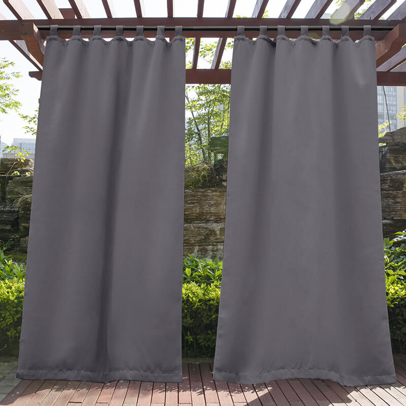 Two gray waterproof tab top outdoor curtains hang on a wooden pergola over a deck, perfect for porch privacy & shade.