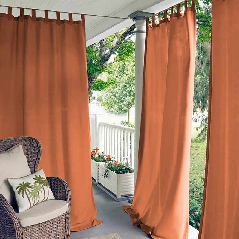 Rust orange waterproof tab top outdoor curtains on a porch deck, providing sun shade and privacy for a cozy patio area.