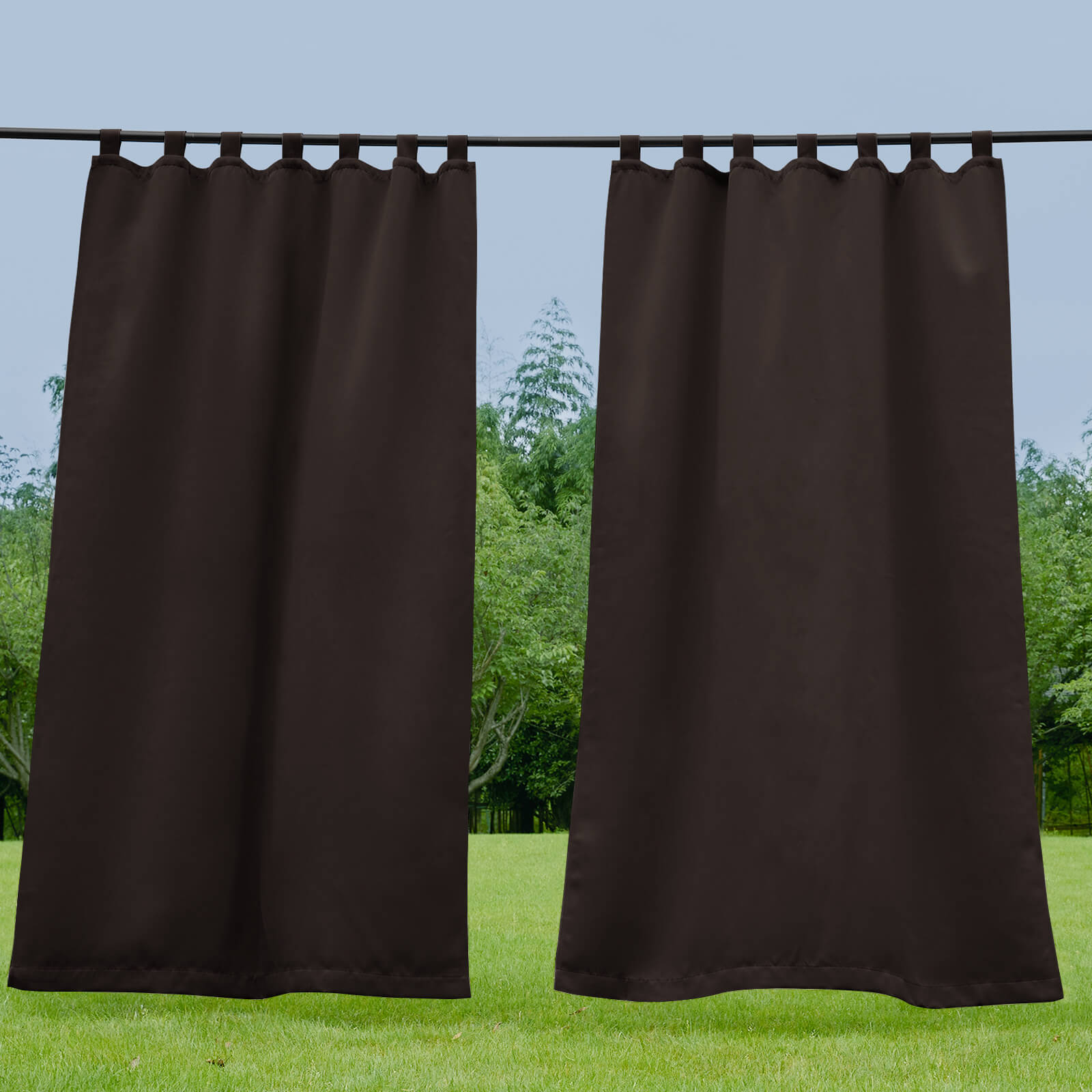 Two dark brown waterproof tab top outdoor curtains for porch or deck, partially open to a lush green yard.