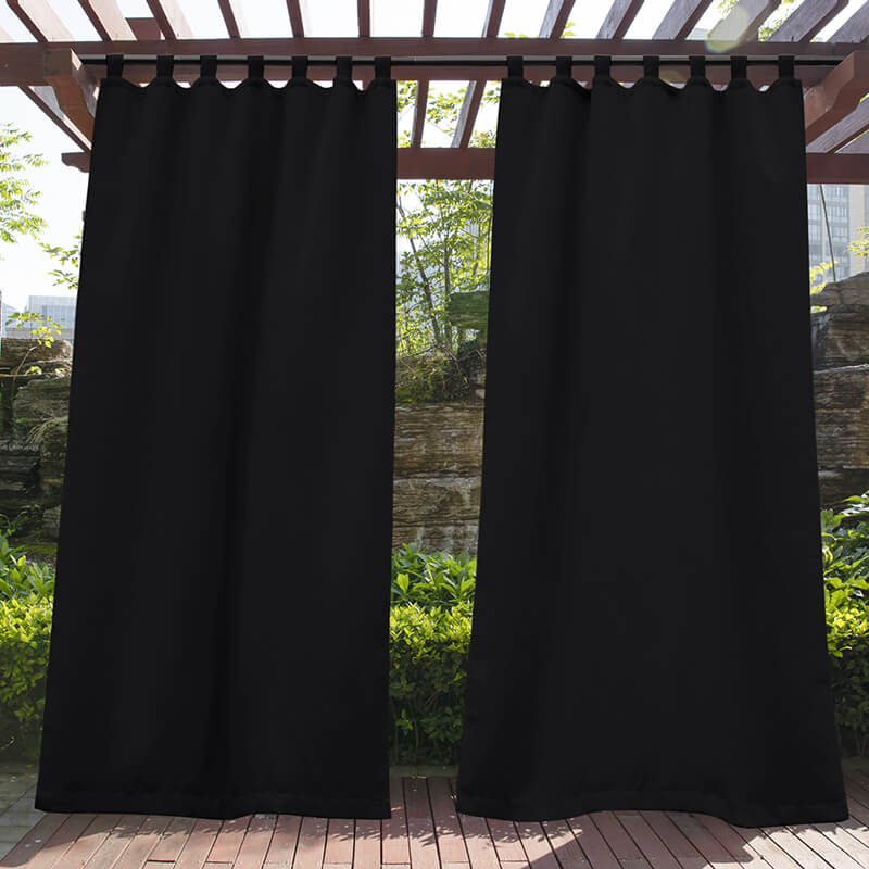 Two black tab top waterproof outdoor curtain panels hanging from a wooden pergola, providing shade and privacy for a deck.