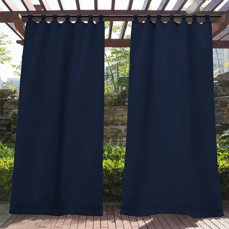 Two navy blue waterproof tab top outdoor curtains on a wooden pergola, creating privacy for a porch deck area.