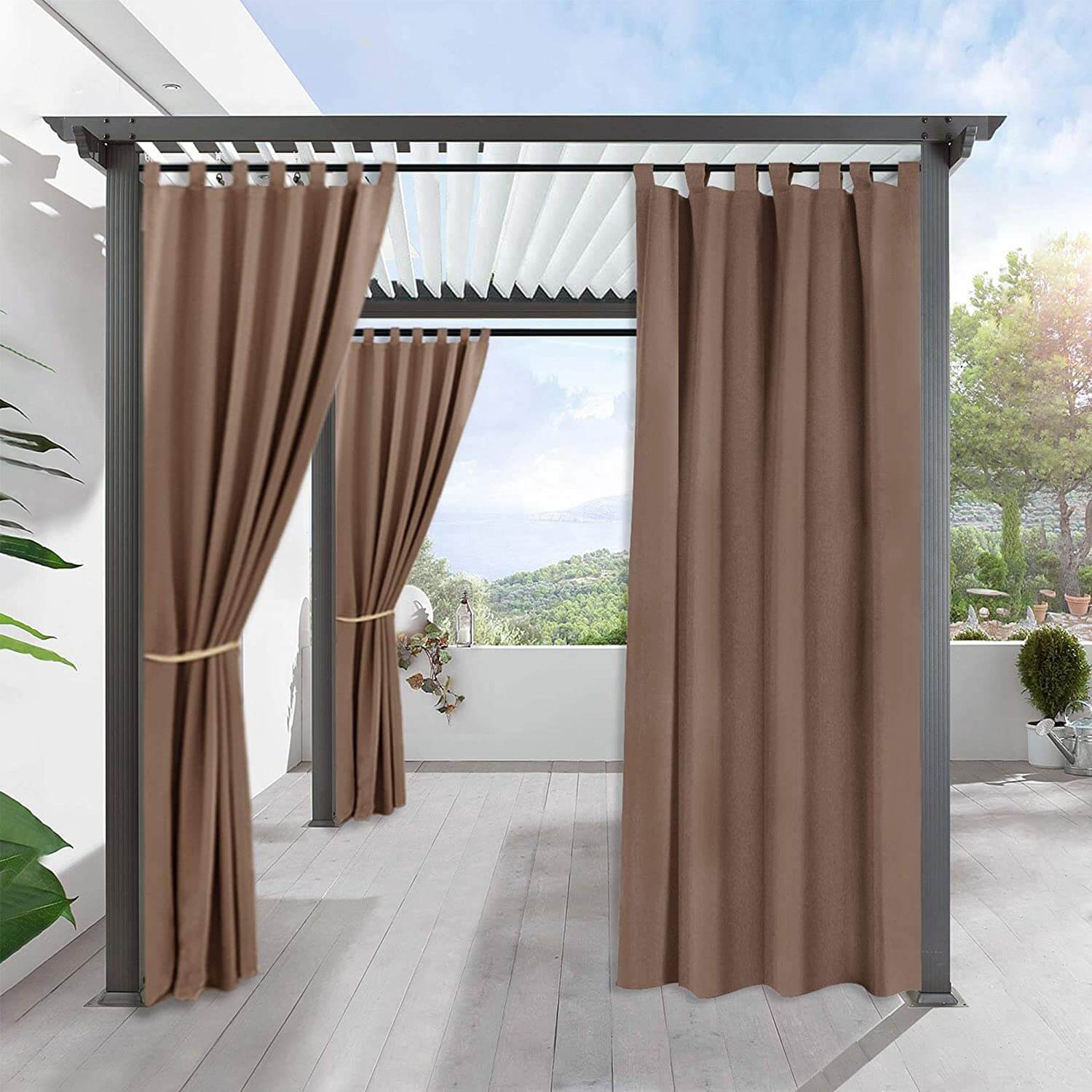 Brown waterproof tab top outdoor curtains on a pergola, tied back and drawn, creating shade on a porch deck.