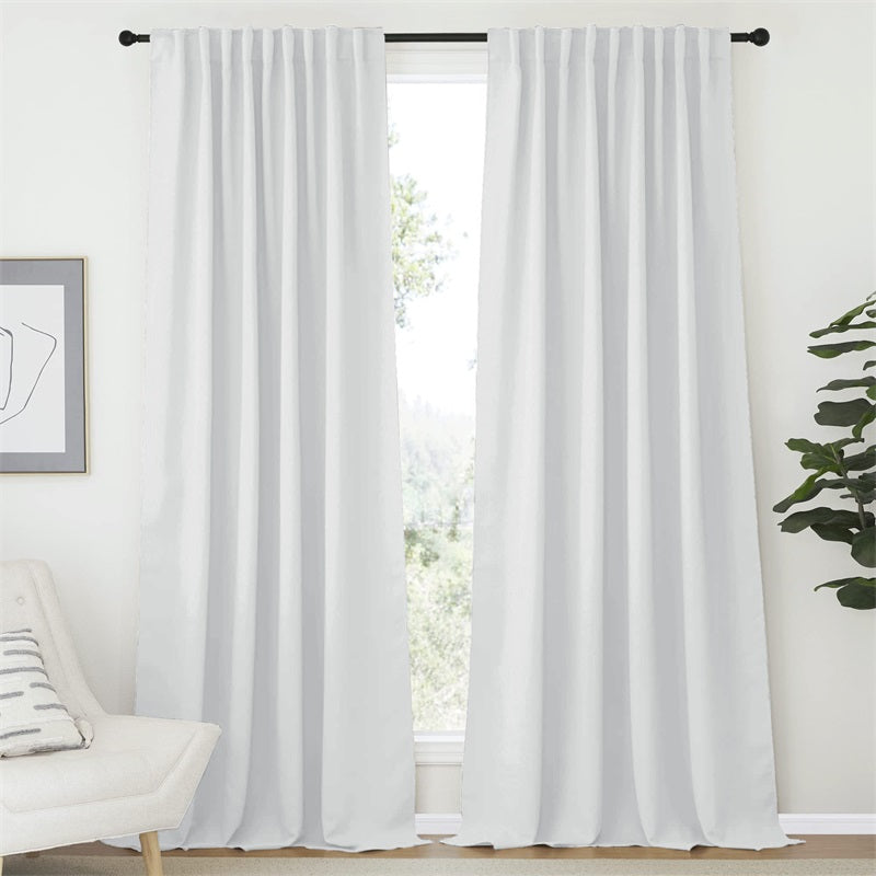 Two 52-inch white rod pocket & back tab blackout curtain panels dressing a living room window for privacy.