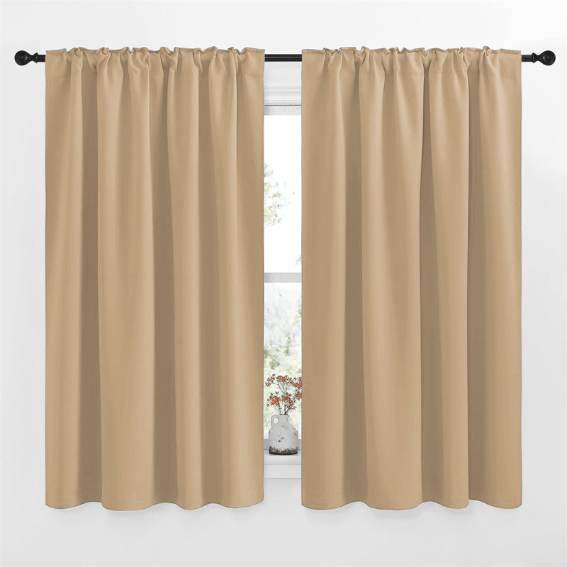 Two 52-inch wide beige rod pocket & back tab blackout curtain panels on a window, ideal for living room or bedroom.
