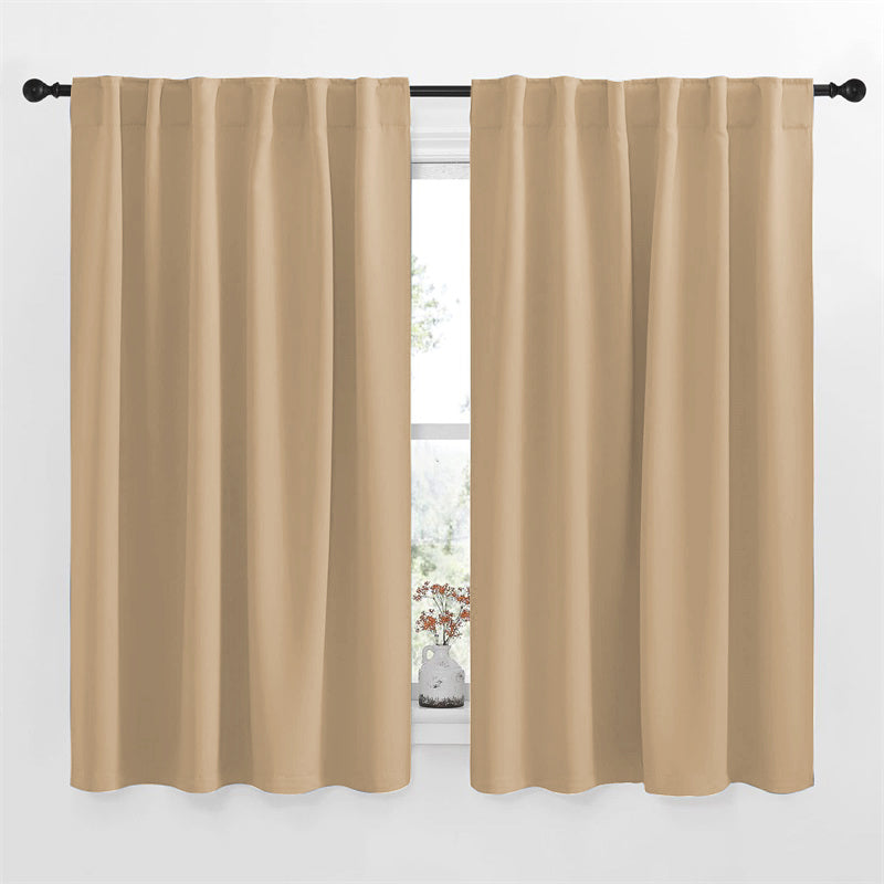 Two beige rod pocket blackout curtains (52 inch width) hanging on a black rod for a living room or bedroom window