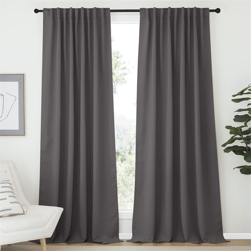 Two charcoal rod pocket blackout curtain panels, 52 inch wide, hung to block light in a stylish living room or bedroom.