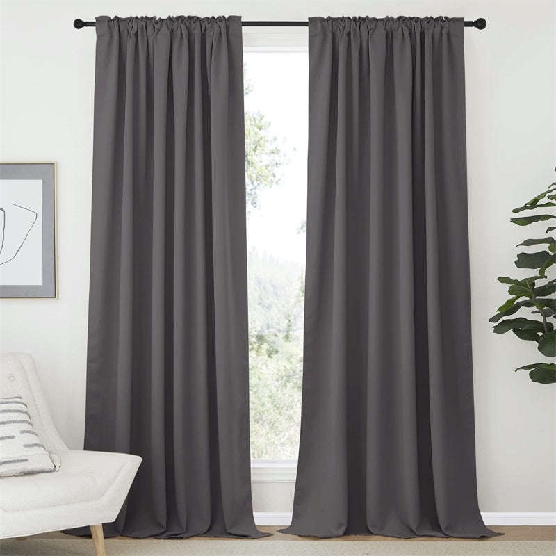 Dark gray blackout curtains with rod pocket and back tab, installed in a bedroom or living room for complete privacy.
