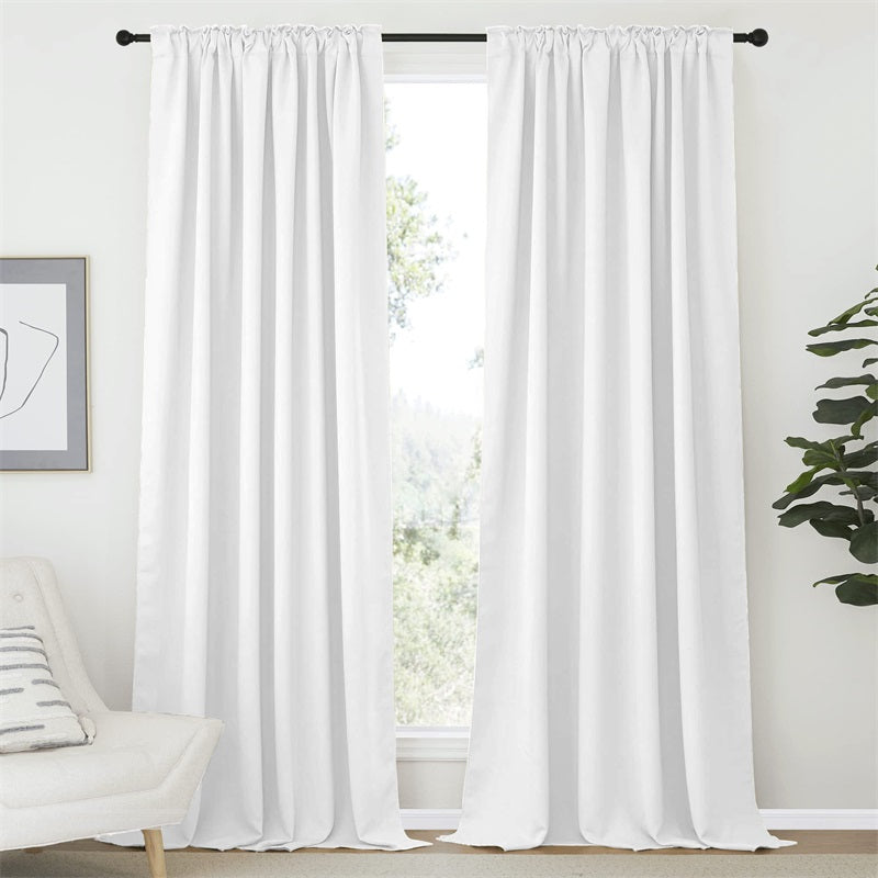 Two pristine white rod pocket & back tab blackout curtain panels covering a bright window, perfect for living room or bedroom.