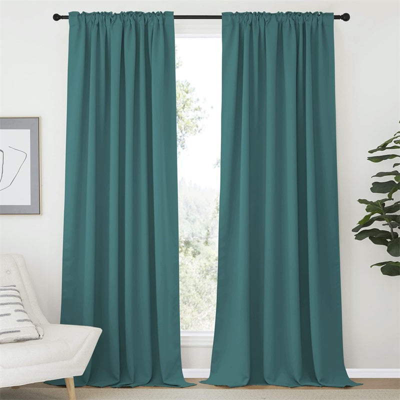Two teal blackout curtains with rod pocket & back tab hang partially open, diffusing light in a stylish living room.