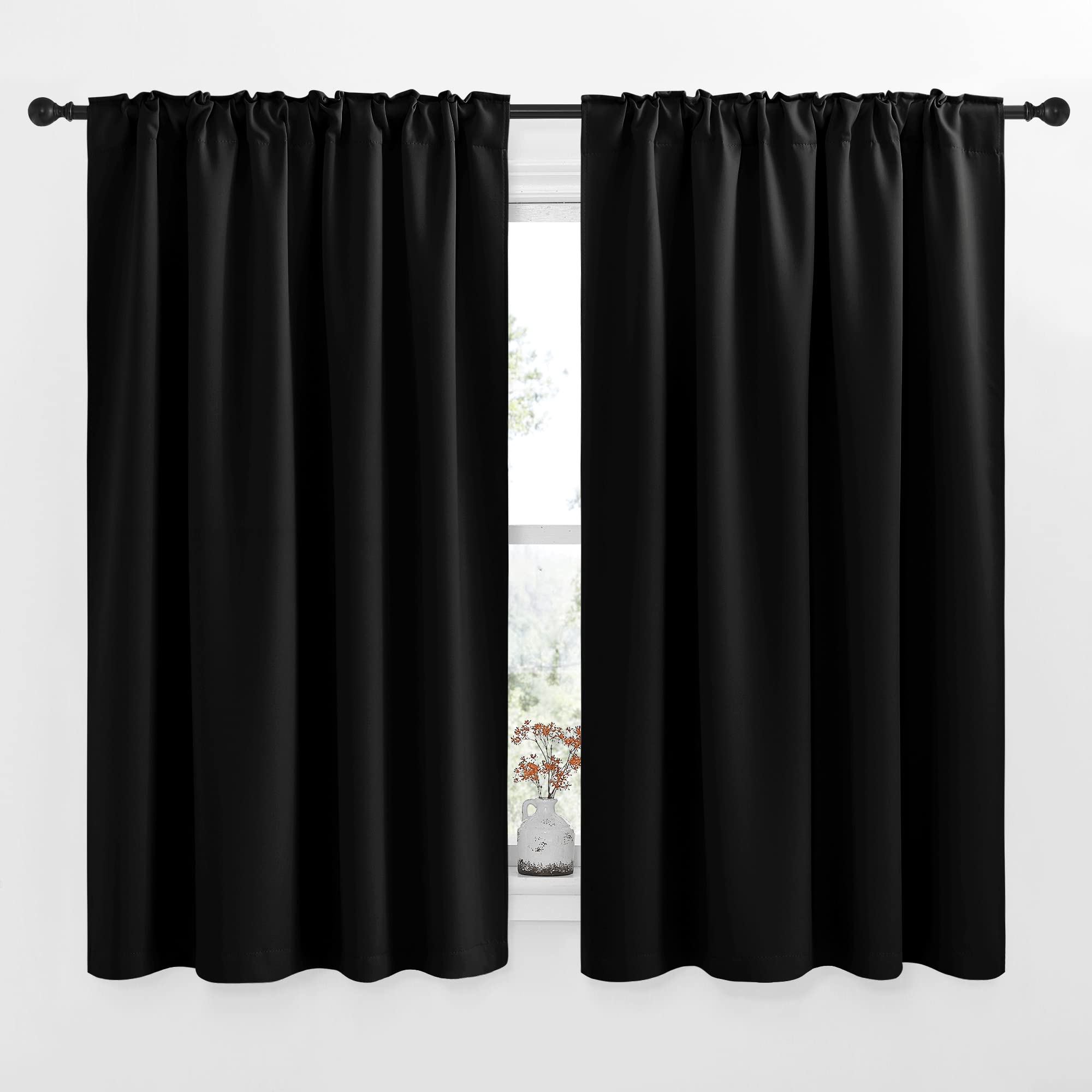 Two 52-inch wide black rod pocket blackout curtain panels for living room or bedroom, partially open over a window with a small vase.