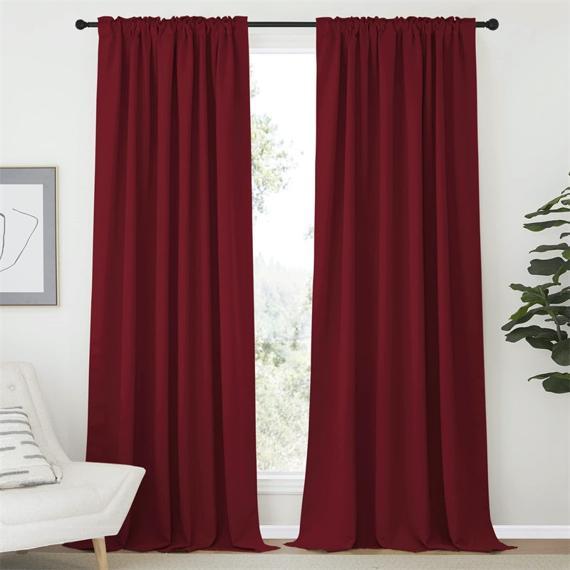 Two 52" wide burgundy rod pocket & back tab blackout curtain panels creating privacy in a living room or bedroom.