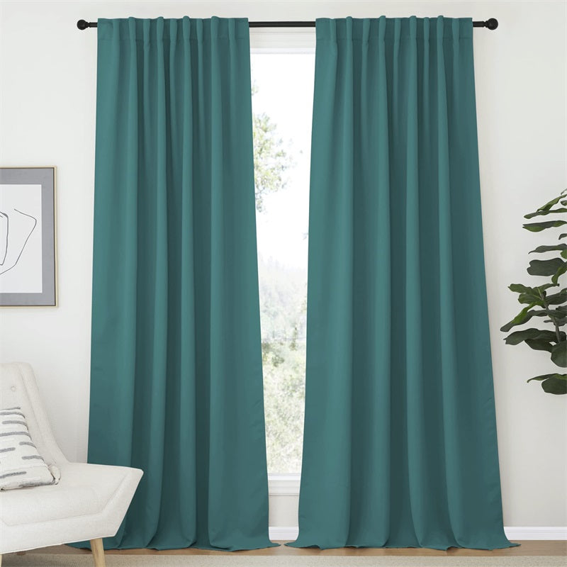 Two teal rod pocket & back tab blackout curtains covering a living room window for enhanced light control.