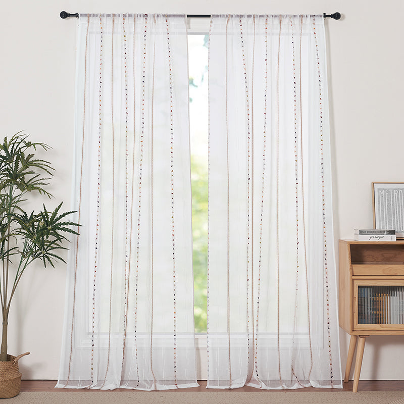 Two white sheer rod pocket curtains with colorful vertical embroidery, offering privacy in a bright living room or bedroom.