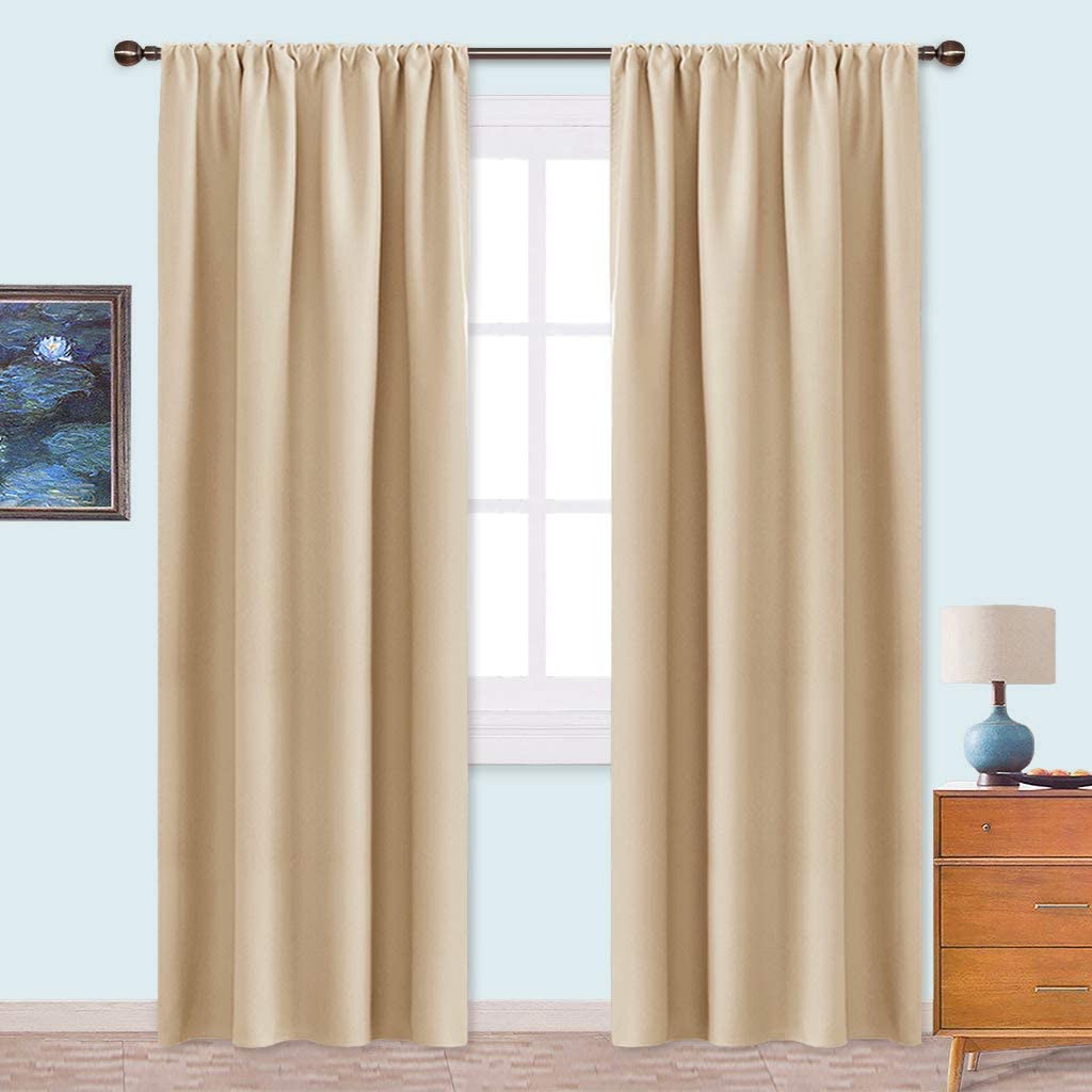Two beige rod pocket triple weave blackout curtains for living room or bedroom, hanging on a window for light control & privacy.