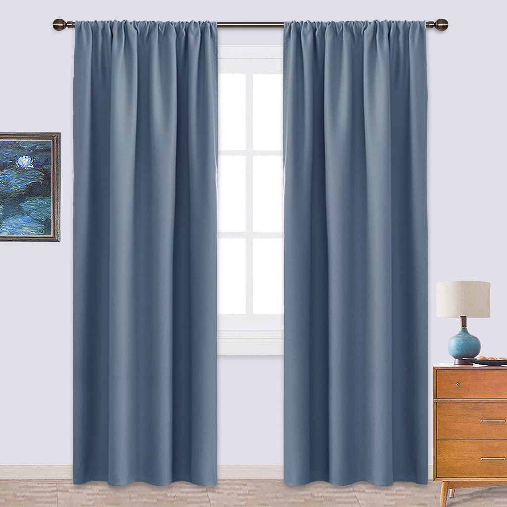 Two slate blue rod pocket triple weave blackout curtains hanging over a window, ideal for living room or bedroom privacy.