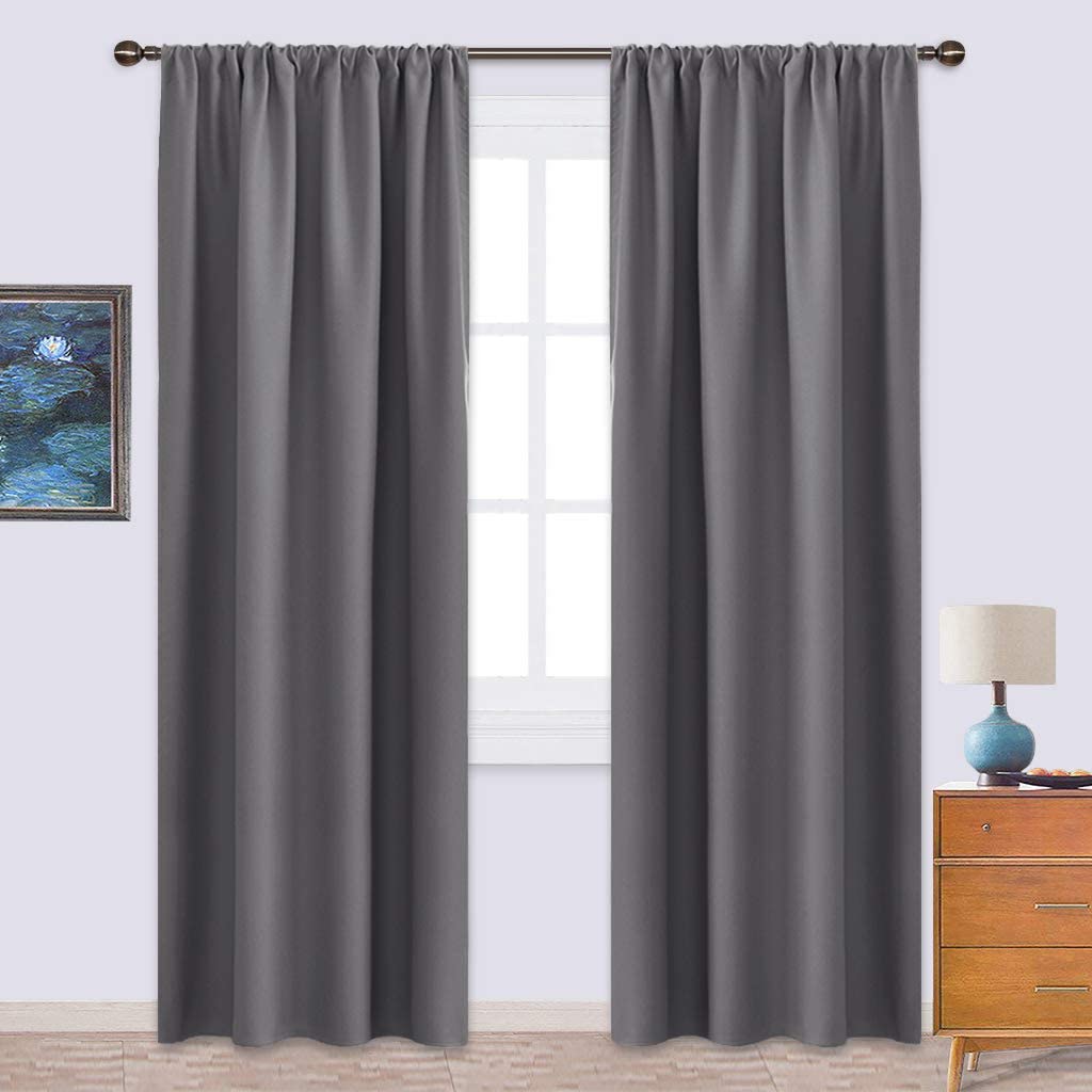 Two panels of charcoal grey triple weave blackout curtains with rod pocket top, hanging over a window in a living room or bedroom.