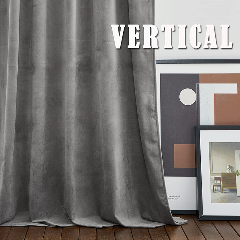Luxurious grey rod pocket velvet blackout curtain with soft folds drapes to a dark wood floor, ideal for elegant living rooms/bedrooms.