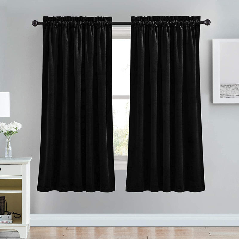 Two luxurious black velvet rod pocket blackout curtain panels for living room or bedroom windows, designed for noise reduction.