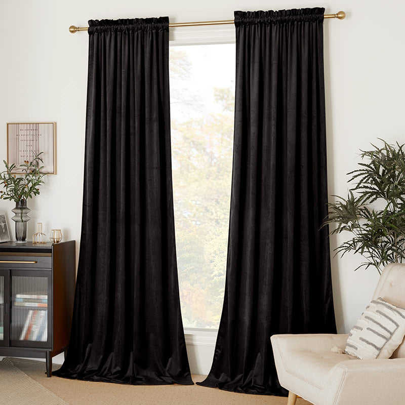 Two black velvet rod pocket blackout curtains covering a living room or bedroom window for privacy and light control.