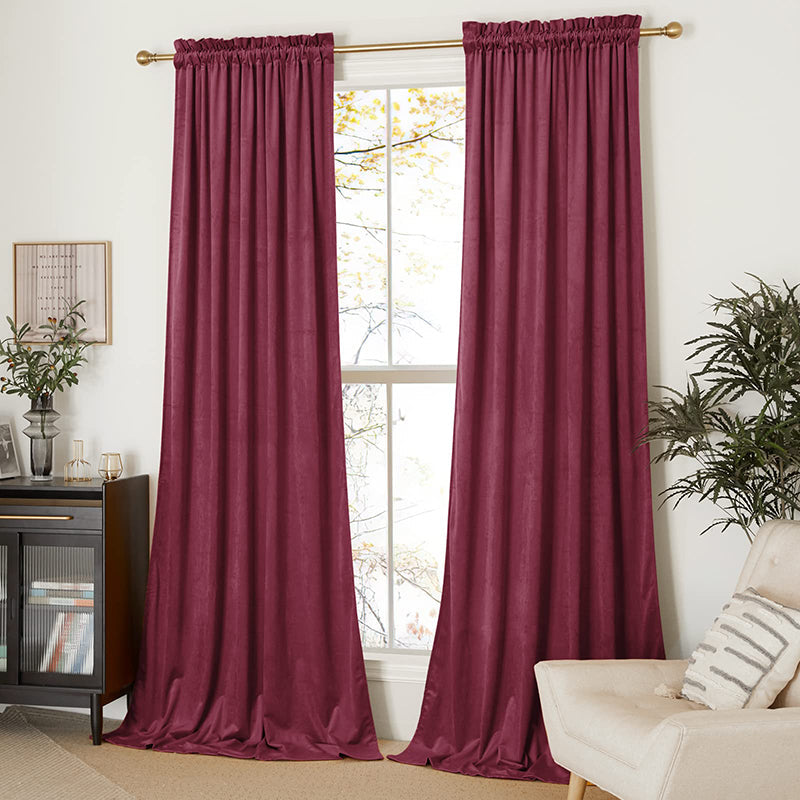Two burgundy velvet rod pocket blackout curtain panels fully covering a window for living room & bedroom privacy.