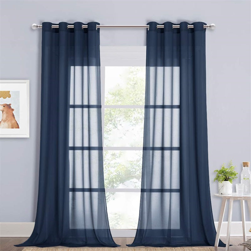 Pair of navy sheer privacy curtains with silver grommets installed on a rod in a bedroom or living room window.