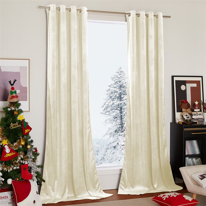 Two cream velvet blackout curtains with silver grommets frame a snowy window view in a cozy living room.