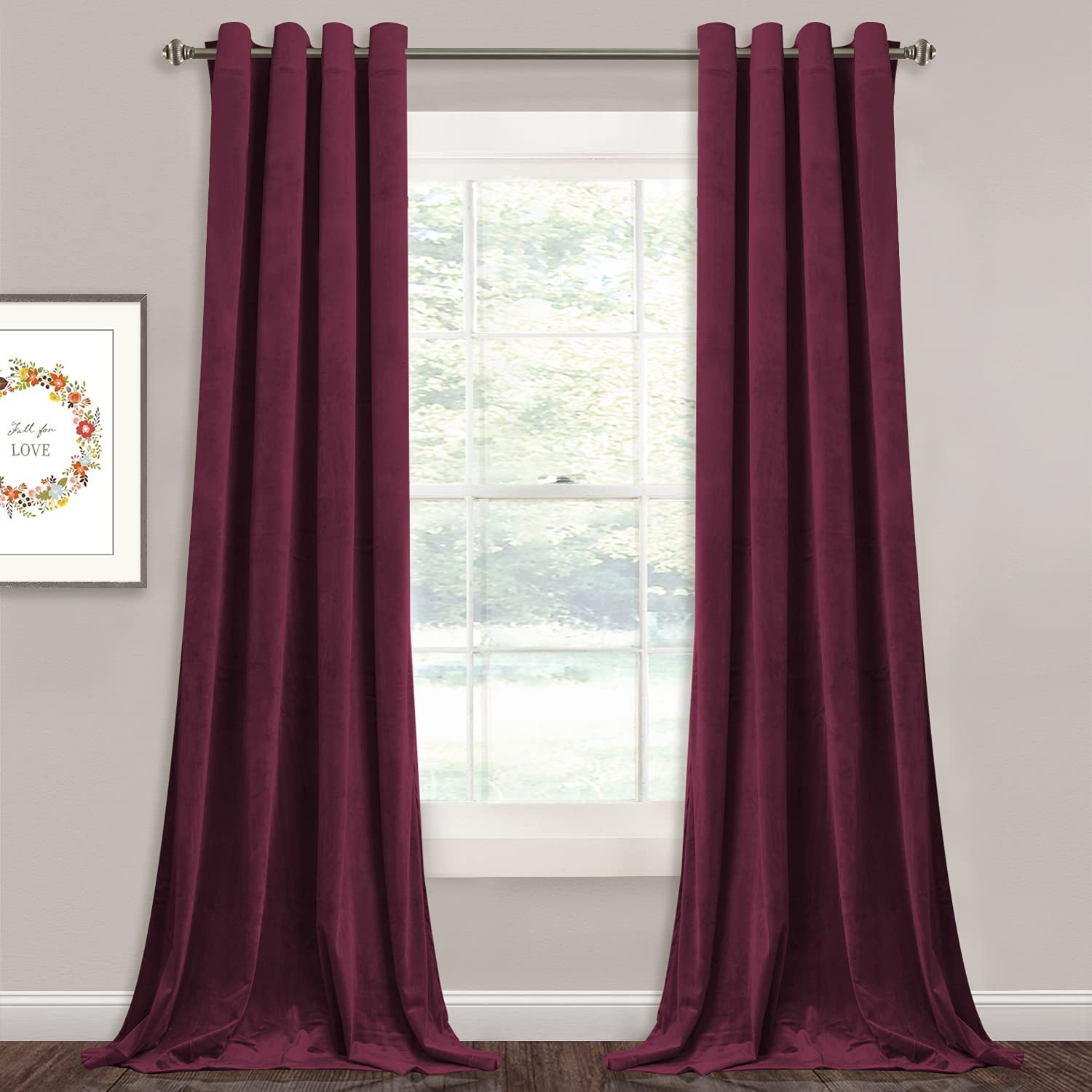 Two deep red velvet blackout curtains with silver grommets, pooling on the floor. Ideal for living room or bedroom decor.