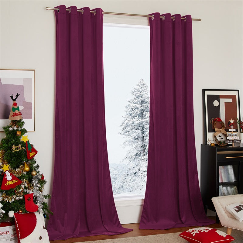 Pair of rich plum velvet blackout curtains with silver grommets in a festive living room, framing a snowy window scene.