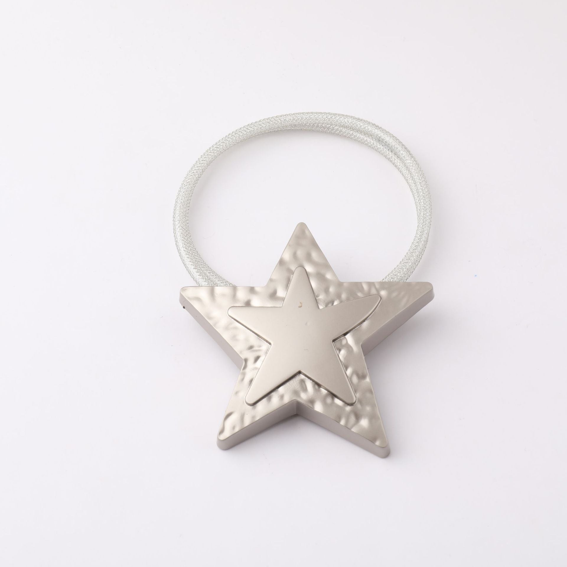 Silver metal star magnetic curtain tieback with textured design and braided strap for patio and outdoor curtains.
