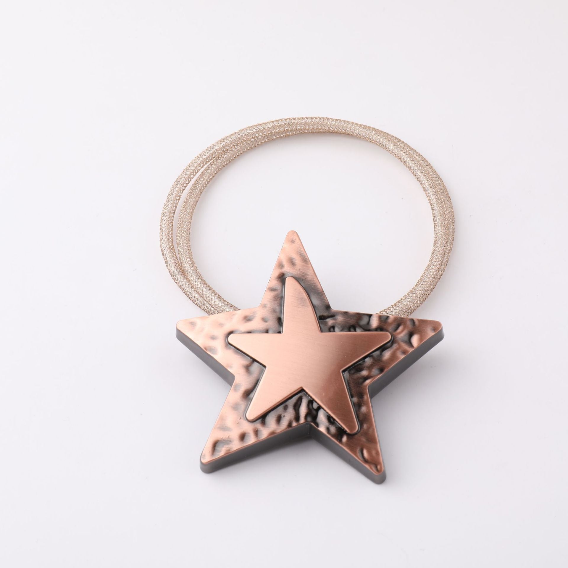 Star-shaped magnetic curtain strap in hammered bronze metal, featuring a decorative design with a woven loop tieback.