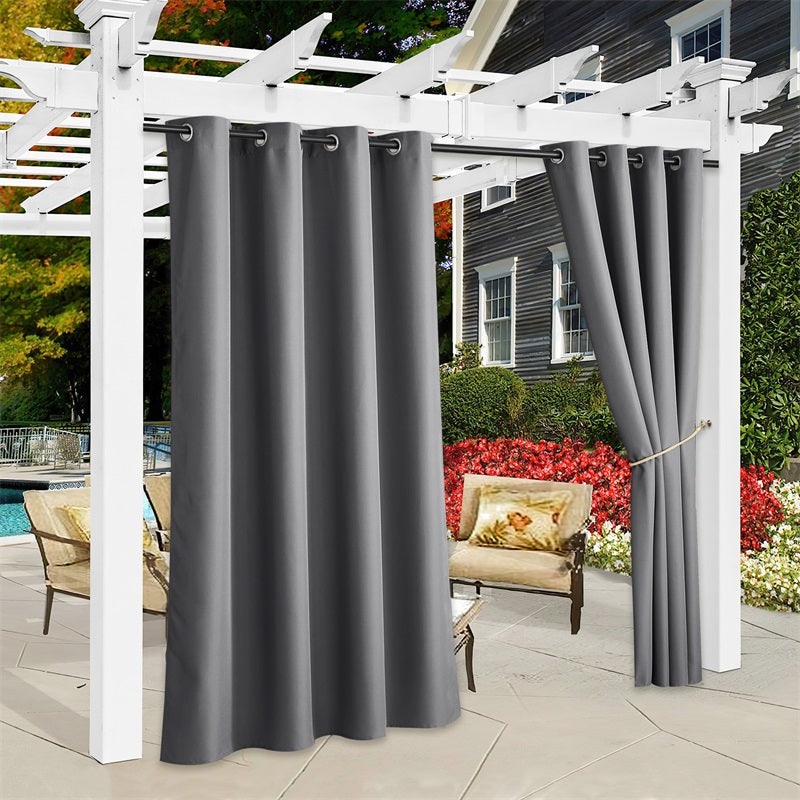 Dark gray waterproof outdoor canvas curtains hanging from a white pergola, with one panel tied back for patio shade.